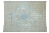 Vintage distressed Birjand carpet with a geometric shield medallion in sky blue, ivory, and sand tones.