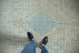 The distressed low-pile texture of a vintage Birjand rug with soft blue geometric Herati motifs.