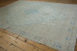 Angled view of a distressed Birjand carpet's shield medallion and time-softened texture.