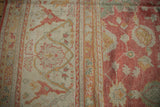 Cinnabar red main border with ivory florals meeting delicate vinery on a vintage Oushak field.