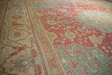 Oushak rug border showing floral arabesques, cinnabar red, ivory, and seafoam green.