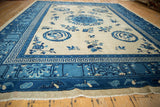 Blue lotus flower, cloud band, and flying bat border designs on antique carpet.