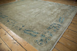 Distressed antique Peking carpet corner showing worn pile, pale blue feather motifs and fringe.