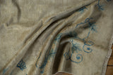 Distressed texture on a draped antique Peking rug with worn ivory pile and blue vine motifs.