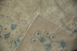 Folded corner of antique Peking carpet revealing distressed ivory pile and blue vine foundation.