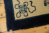 Antique Peking rug corner, deep indigo border, cobalt line, beige field, intact selvage.