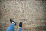 Textured distressed vintage Oushak rug with soft mauve, rose, and ivory floral vine patterns.