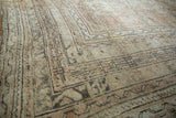 Distressed vintage Oushak carpet corner with meandering vine borders and faded floral field.