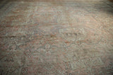 Textured, distressed Oushak rug surface with muted dusty rose, beige, and charcoal patterns.