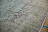 Distressed vintage Sivas carpet showing faded floral palmettes, seafoam green, aubergine, and wear.