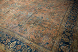 Vintage Mahal carpet detail: dusty terracotta field, ornate floral vinery, navy blue border.