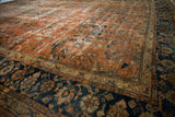 Ornate floral vinery on vintage Mahal carpet, showing terracotta field and navy border.