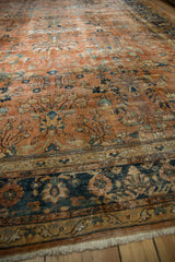Vintage Persian Mahal carpet corner, showcasing navy blue floral border, terracotta field, and fringe.