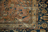 Floral vinery on terracotta field meeting ornate navy border of a vintage Mahal carpet.