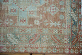 Texture detail of a distressed Persian Karaja rug showing worn pile and pinwheel motifs in seafoam and dusty blush.