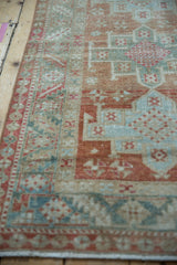 Textured low pile of a distressed Karaja rug with seafoam green and pale red geometric designs.