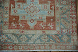 Corner detail of a distressed Karaja rug with geometric borders in seafoam, sand, and dusty blush.