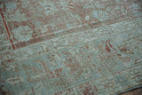Distressed Malayer carpet texture with faded seafoam green and dusty rose floral patterns.
