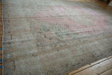 Faded pink and beige distressed pile, revealing faint foundation and a meandering vine border.