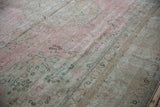 Distressed Meshed carpet showing mostly even wear, highlighting faded pink, beige, and seafoam green hues.