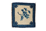 Vintage Peking square mat features an ivory field, blue floral branch, and key corner motifs, 1'2