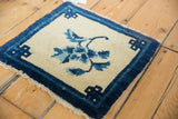 Vintage Peking rug corner with indigo border, ivory field, and infinity knot motif.