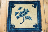 Cobalt blue infinity knot motif on ivory field of a Chinese Peking rug corner.
