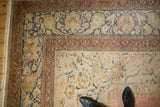 Distressed Kayseri rug corner with intricate floral vines, faded rose, blue, and varying pile texture.