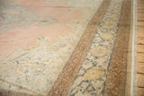 Distressed Kayseri rug, faded pink field with intricate florals, and patterned side selvage.