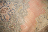 Distressed pink field with faded blue and beige floral patterns at Kayseri rug corner.