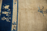 Vintage Peking carpet's cobalt blue pictorial border, ivory motifs, and expansive neutral field.