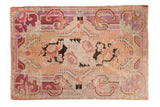 Distressed vintage Khotan carpet, oversized floral pattern in dusty blush and faded violet.