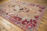 Distressed vintage Khotan rug corner with curvilinear border and muted floral motifs.