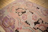 Distressed vintage Khotan carpet with faded dusty blush, pale violet, and dark brown oversize floral motifs.