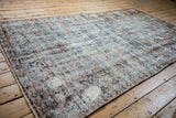 Distressed Baktiari carpet texture with faded multi-panel patterns and visible foundation.