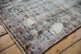 Distressed vintage Baktiari rug detail showing worn texture, exposed foundation, secured edge.