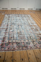 Distressed vintage Baktiari carpet texture, showing worn dusty red, blue, and ivory panels.