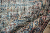 Worn pile texture of the distressed Baktiari rug, revealing muted blue, red, and ivory panel designs.