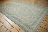 Angled view of a distressed Sivas carpet showing its low pile and allover boteh design in pale blue and cream.