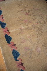 Beige textured pile of an antique Chinese Art Deco rug with pink blossoms, blue border.