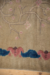 Beige ground of a Chinese Art Deco rug showing pink cherry blossoms and cobalt blue bat motif.