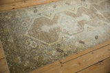 Corner view of distressed Hamadan rug's serrated leaf border and geometric field, with earthy tones.