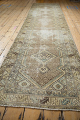 Geometric diamond medallions and serrated leaf border on a distressed Hamadan runner.