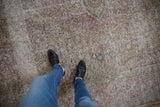 Distressed vintage Tabriz rug texture with visible knot heads and time-softened purple and ivory colors.