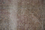 Close-up of a vintage Persian Tabriz carpet showing visible wear to the foundation and knot heads.