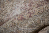 Hand-knotted weave and distressed texture on the rolled corner of a vintage Tabriz rug.