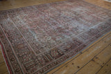 Distressed floral and geometric patterns in faded rose and brown on a vintage Persian carpet.