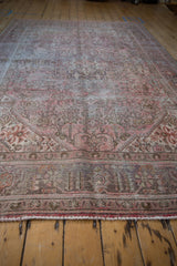 Faded pink and brown distressed vintage rug with worn pile, visible foundation, and fringe.