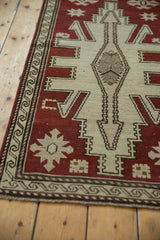 Distressed Oushak runner detail showing ivory geometric pattern, wave border, and worn pile.