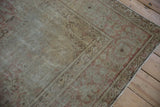 Distressed corner of vintage Kayseri rug with muted floral border and worn beige pile.